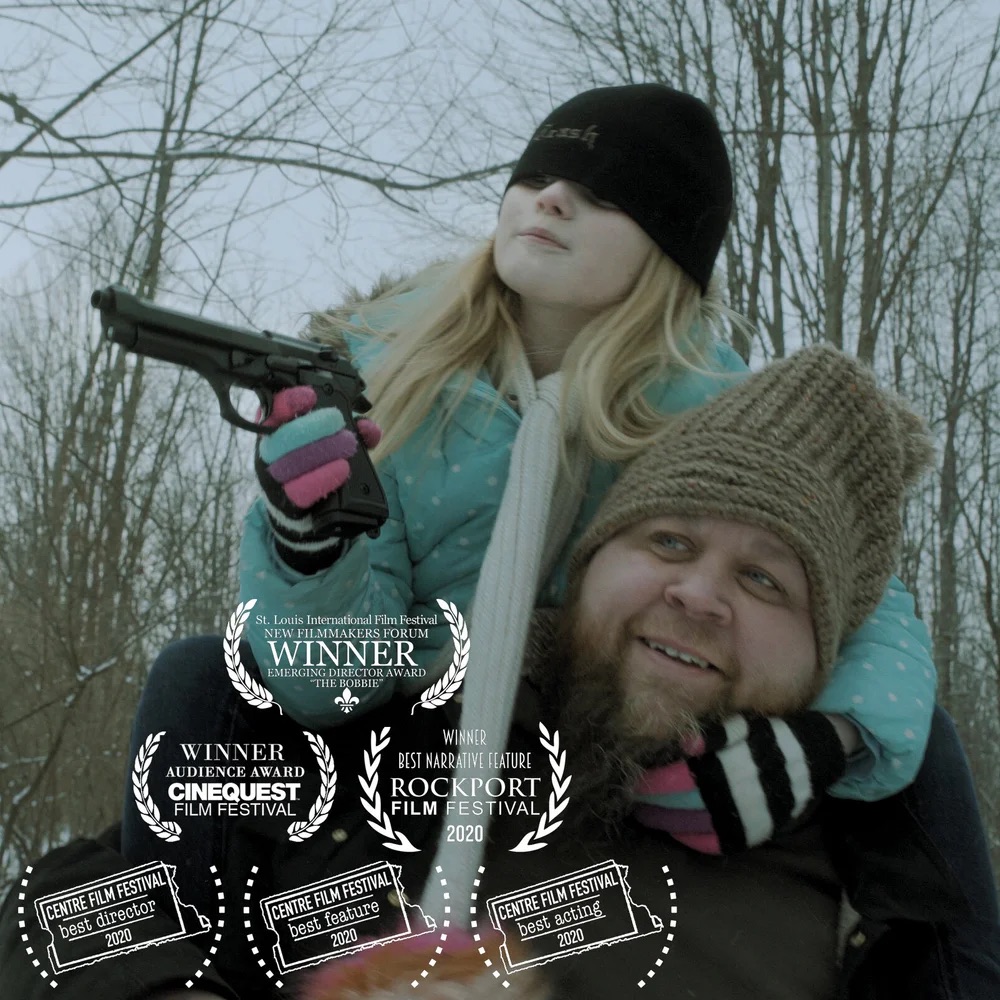 A girl in a hat holds a toy gun on a man’s shoulders: still from Small Time, with festival laurels